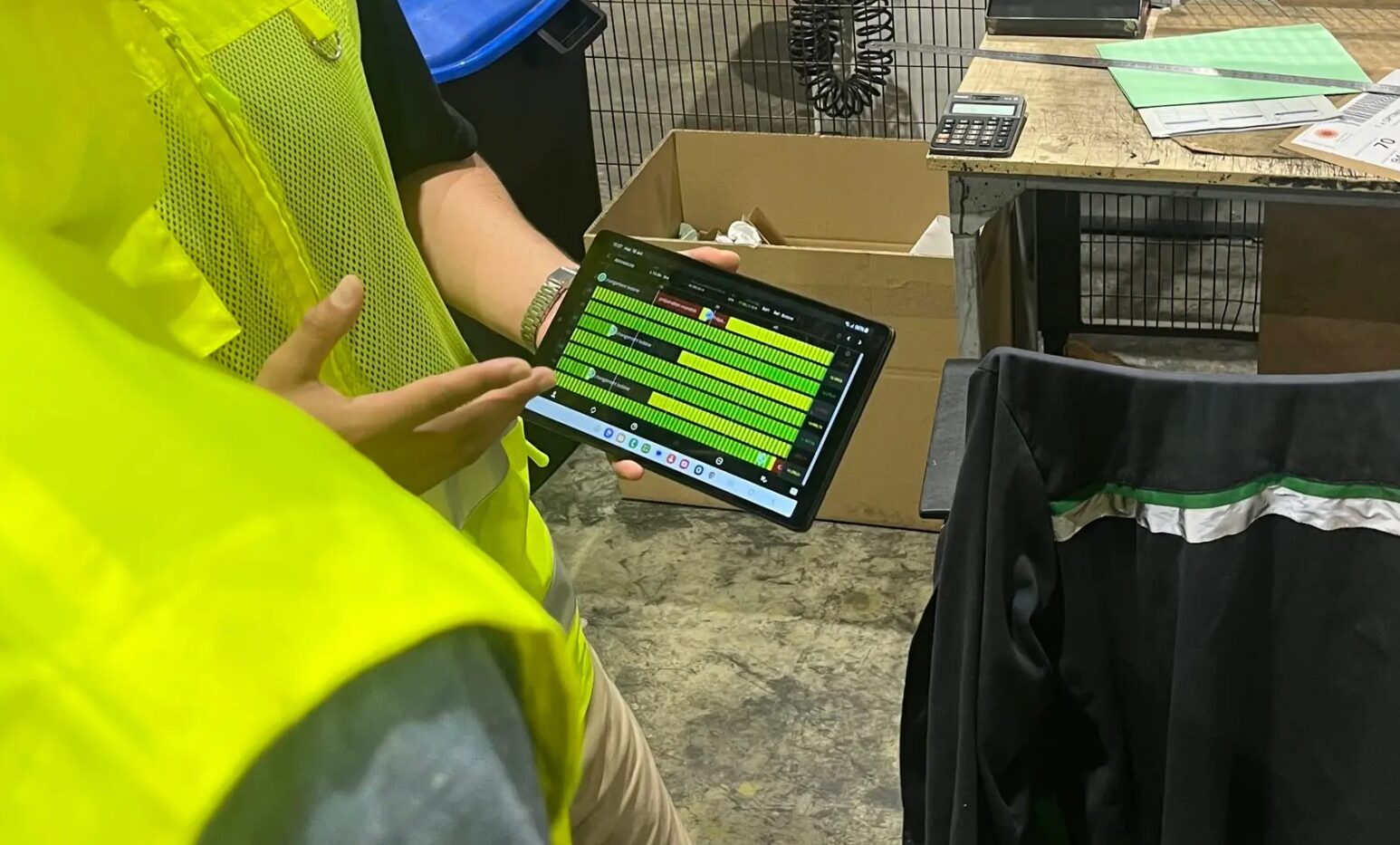 Operators on a factory floor monitoring production on the Evocon Shift View on a tablet