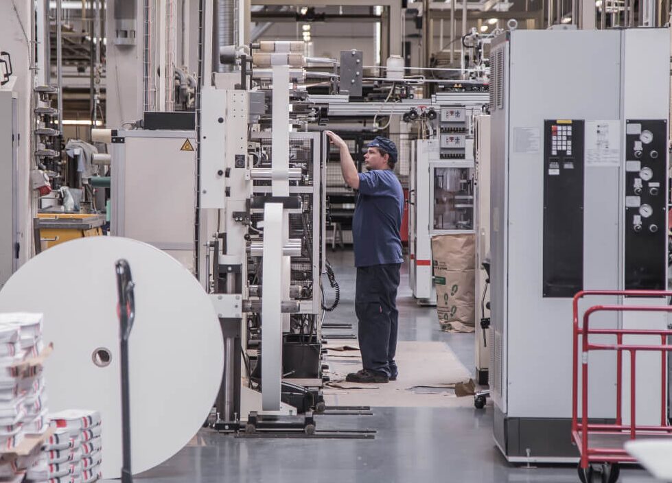 A factory operator at AIP's Danish manufacturing plant adjusting settings on a large industrial control panel.