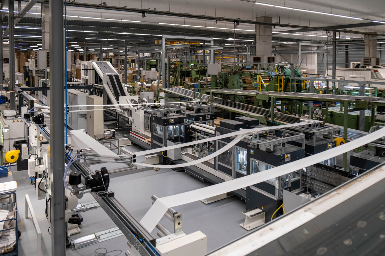 Overview of AIP's automated production line in a Dutch factory with specialized paper processing equipment and conveyor systems.
